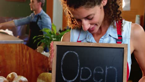 female staff holding a open sign slate in supermarket