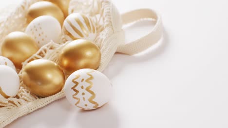 Bag-with-white-and-gold-easter-eggs-on-white-background-with-copy-space