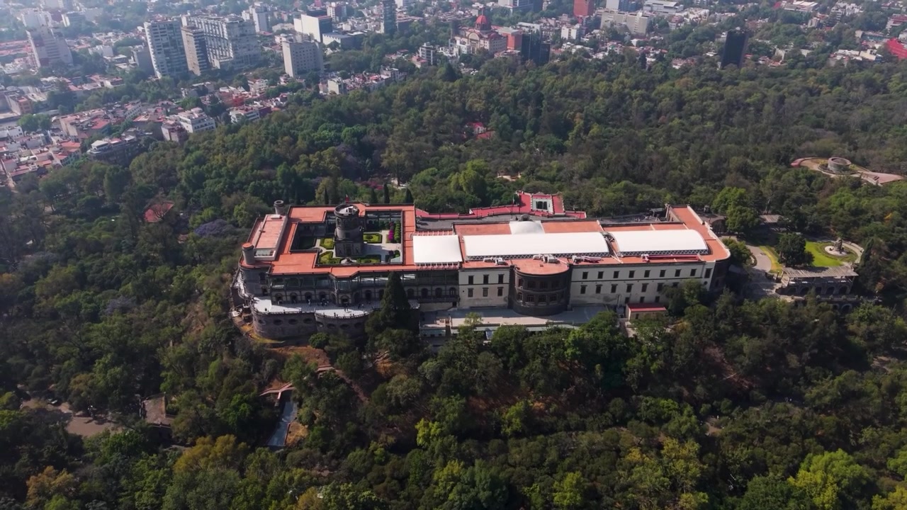 Una vista aerea mozzafiato da drone, con angolazione elevata e cinematografica, che cattura lo storico Castello di Chapultepec (Castillo de Chapultepec) arroccato maestosamente in cima alla collina di Chapultepec in mezzo alla fitta e vasta foresta