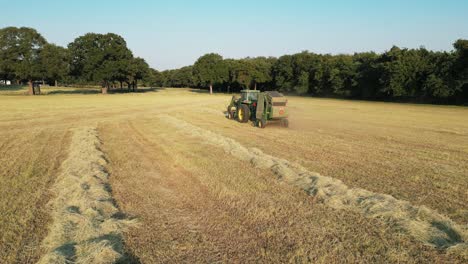 disparo de seguimiento a baja altitud del tractor tirando detrás de la empacadora de heno redonda