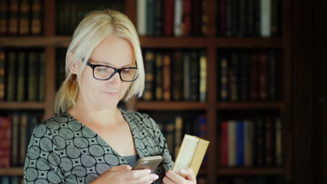 woman holding book using smartphone