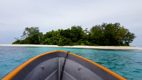barco que se dirige hacia una pequeña isla tropical con agua turquesa en las islas salomón
