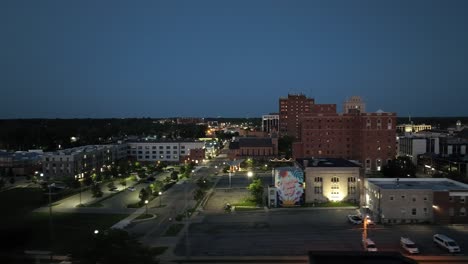 jackson, michigan en el centro de la ciudad por la noche con un video de avión no tripulado de tiro ancho moviéndose de izquierda a derecha