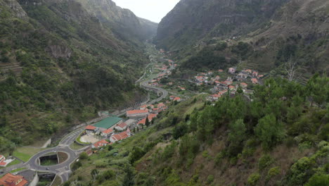 woman admiring scenic town on foothills of green mountain at daytime in madeira island, portugal