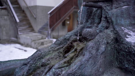 small stream of water streaming out of fountain in idyllic town - close - 100fps