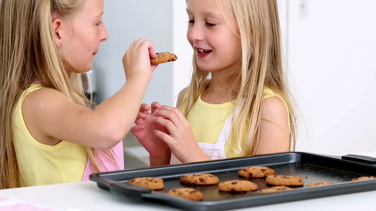 Sisters feeding each other fresh cookies