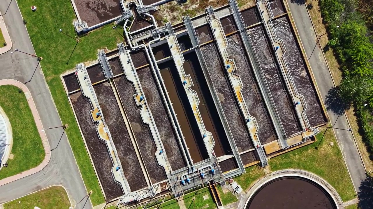 Water treatment facility shows multiple tanks working to clean wastewater during sunny day in urban area