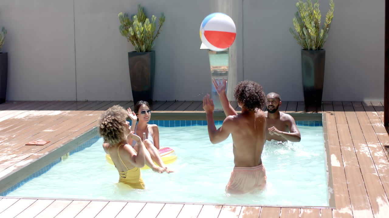 Playing with beach ball, Diverse friends enjoying pool party on sunny day