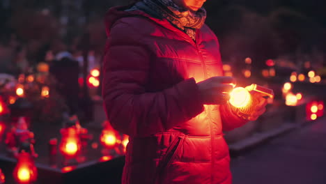 Woman-lighting-a-candle-in-a-cemetry-at-night