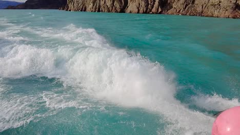 Mix-of-a-turquoise-water-getting-thrusted-by-a-propeller,-a-sunset-and-majestic-mountains-in-the-horizon