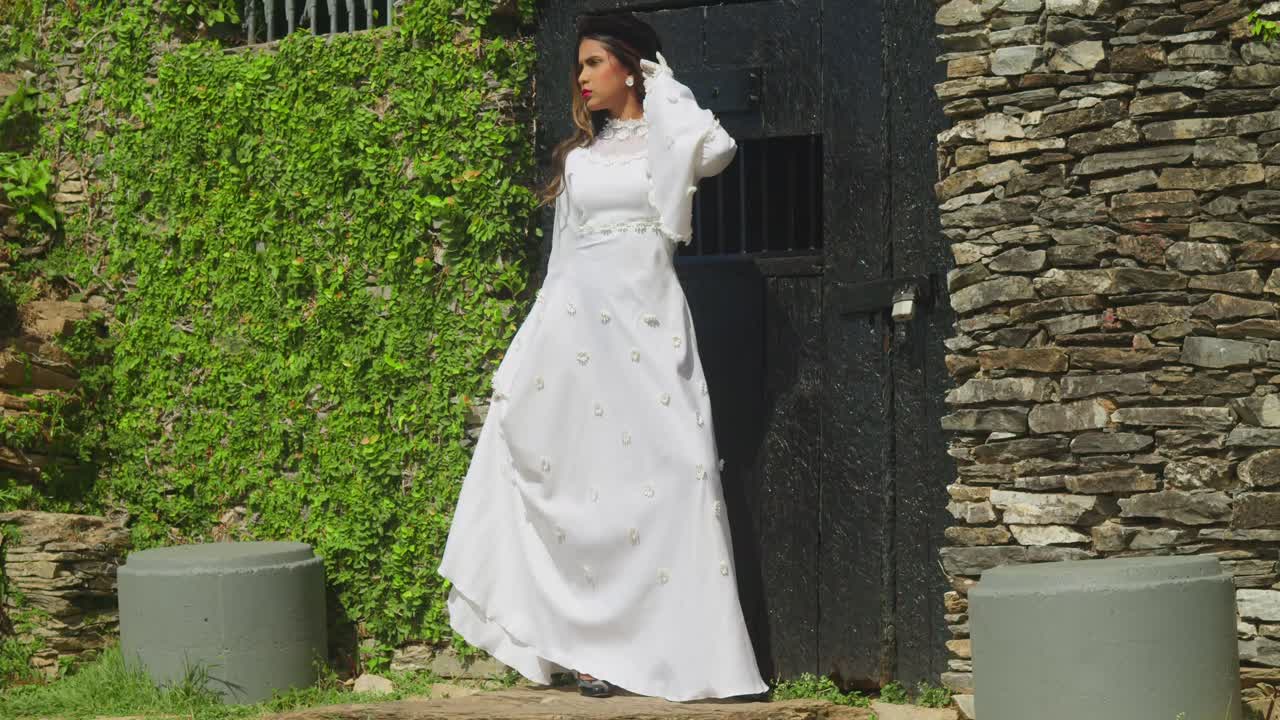 A child in a vintage wedding gown strolling through the ruins of an old fort.