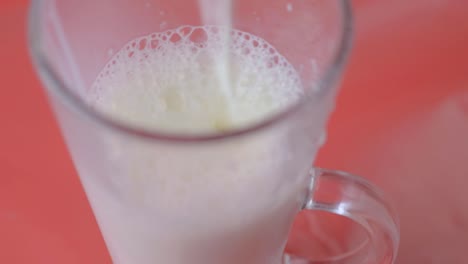 pouring milk into a glass on a red background