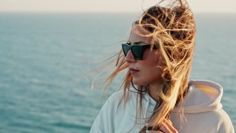 beautiful profile shot of lady wearing sunglasses , her hair flying in strong wind