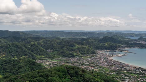 Weit-Offener-Zeitraffer-über-Einer-Kleinen-Stadt-Am-Meer-Mit-Sanften-Hügeln,-Meer-Und-Wolken---Schwenk