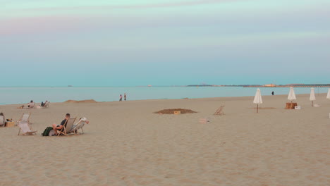 people relaxing on sopot beach at dusk with pastel sky and calm waters in the background