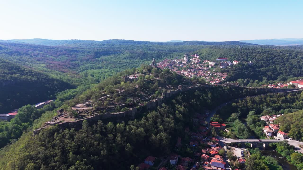 Gradual rising shot of Tsaravets hill, crowned by the historic fortress, set against the lush Bulgarian landscape.