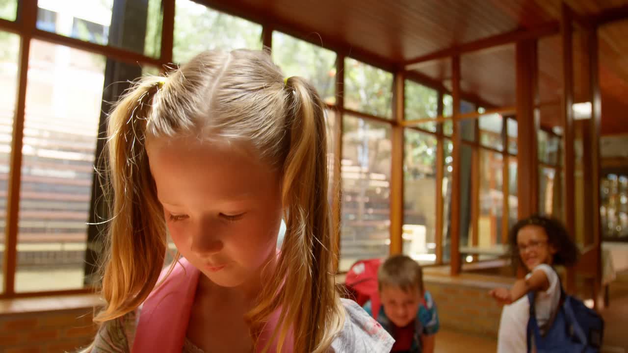Skolebørn mobber en trist pige på gangen på en folkeskole 4K