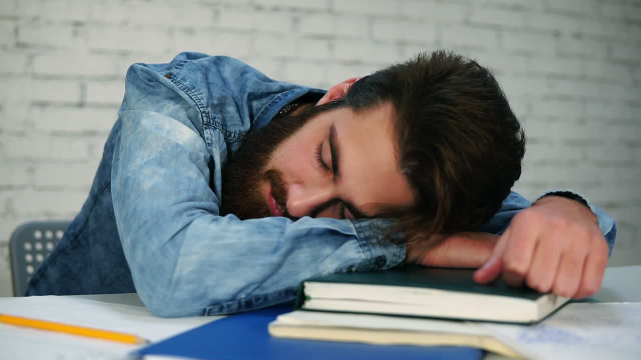 Close Up view of young office worker or student sleeping at the table with notebooks on the table