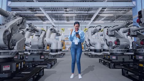 mujer celebrando el éxito en una fábrica moderna con robots