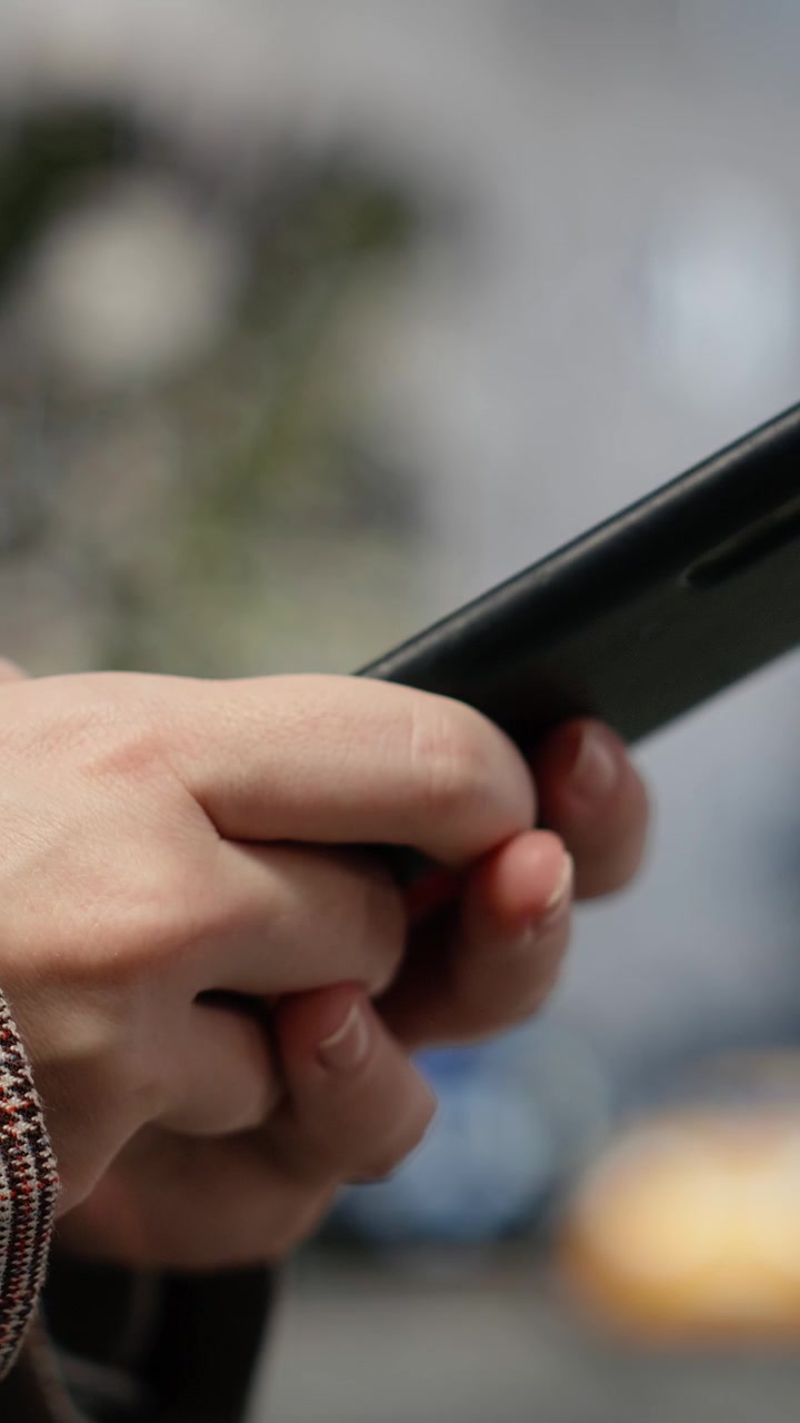 Video verticale: Donna d'affari che usa il touchscreen dello smartphone, primo piano su sfondo cittadino