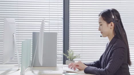 woman working in an office with a headset and computer