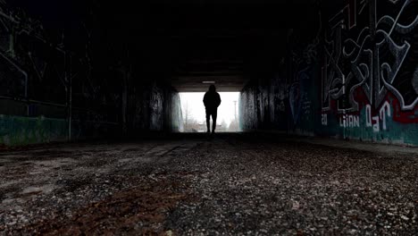 silhouette of a man walking in a dark tunnel