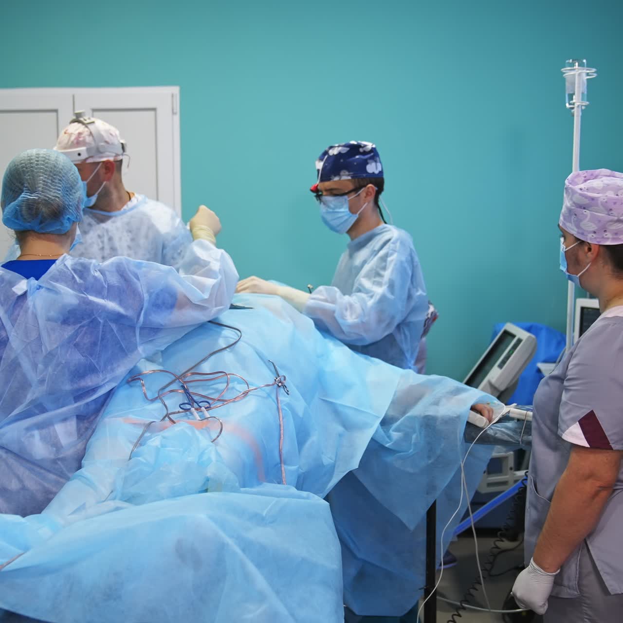 Male doctors and female nurses cooperating at operation in surgery room. Surgeon throws the used sponge into bin from a distance