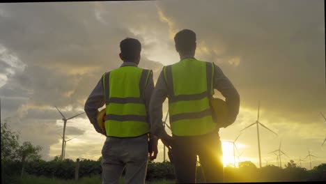 teamwork of asian windmill engineer group, worker working, shaking hands on site at wind turbines field or farm, renewable clean energy source. eco technology for electric power. industry. people