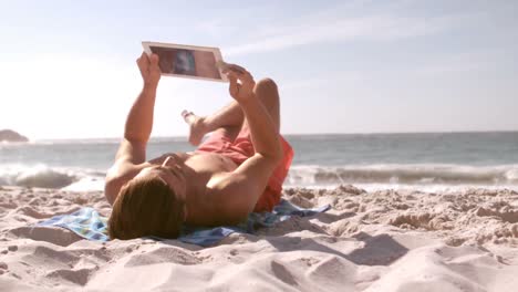 Man-lying-on-his-back-and-using-his-tablet