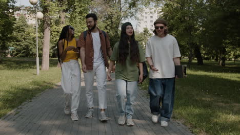 four friends walking and chatting in a sunny park