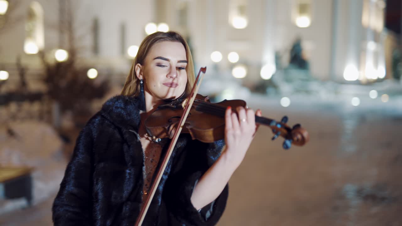 Young lady playing the violin on the street. Violinist playing in the middle of the street with luxury background