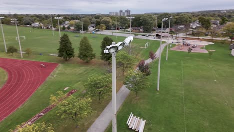 drone shot circling around a large sports field light during the day with high school track in background