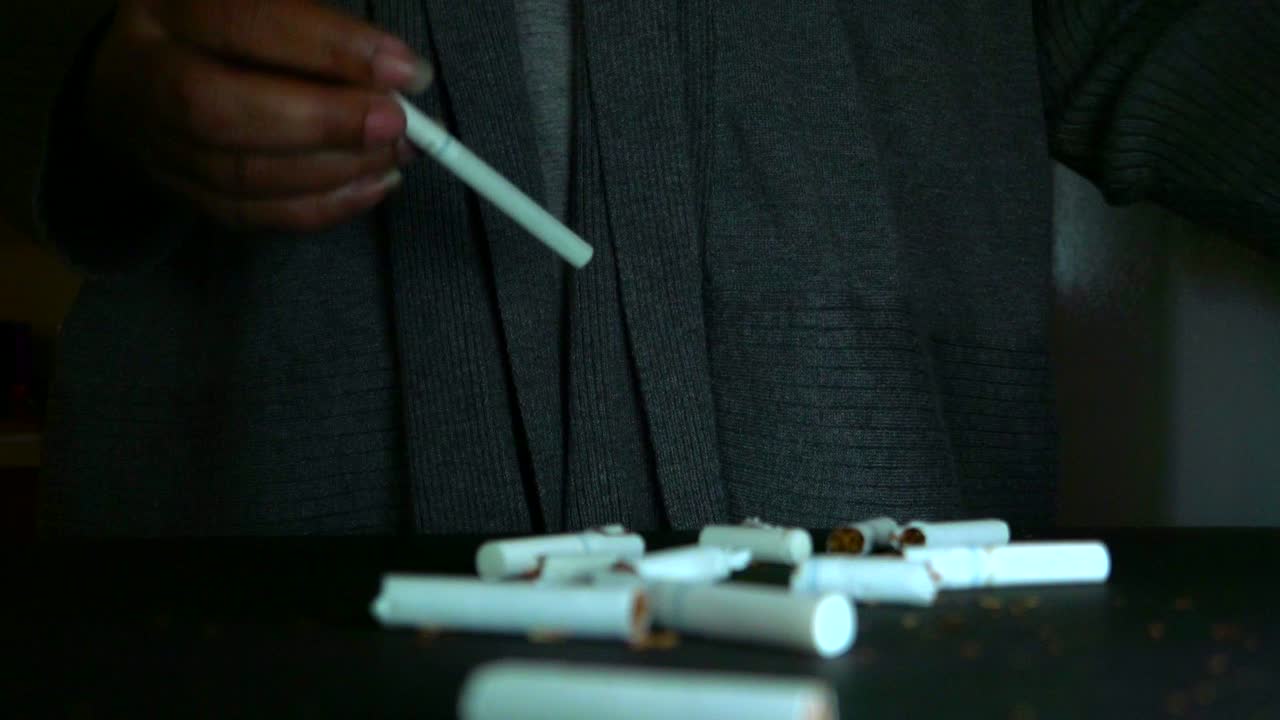 manos femeninas afroamericanas rompiendo cigarrillos para dejar de fumar