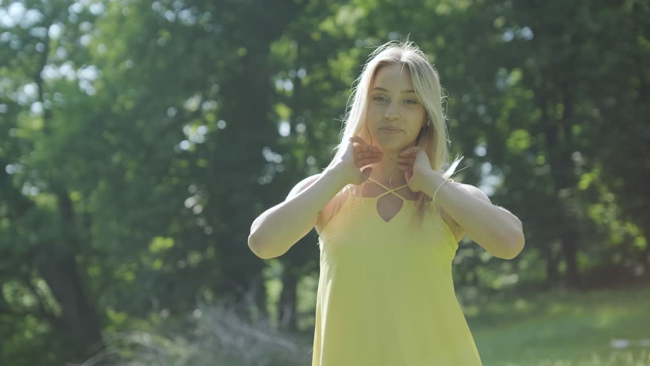 Kvinde i gul kjole danser yndefuldt i sommerpark