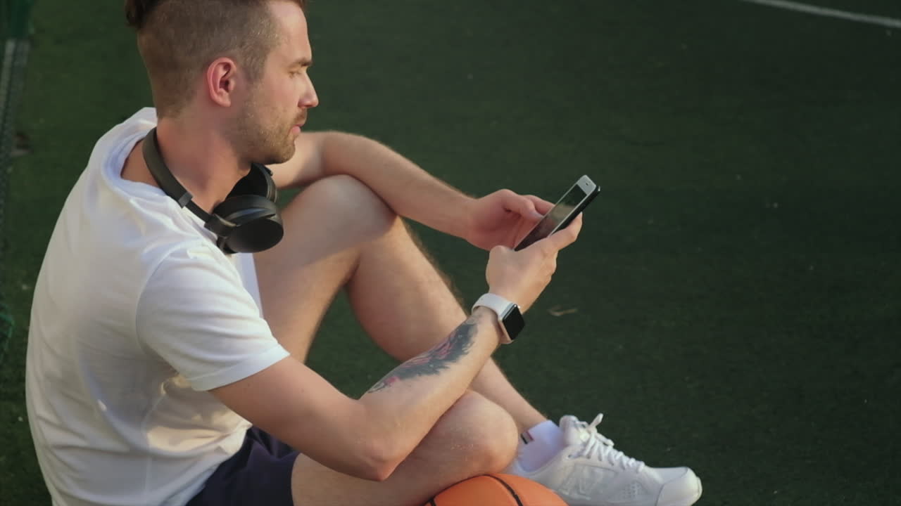 hombre usando el teléfono en una cancha de baloncesto