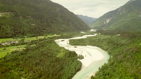 aerial view of soca river surrounded by a small town and many hills in slovenia.