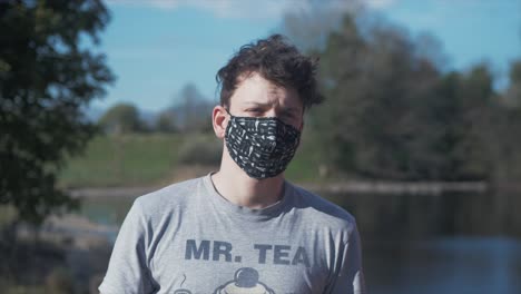 man putting on black homemade cotton corona virus mask medium shot