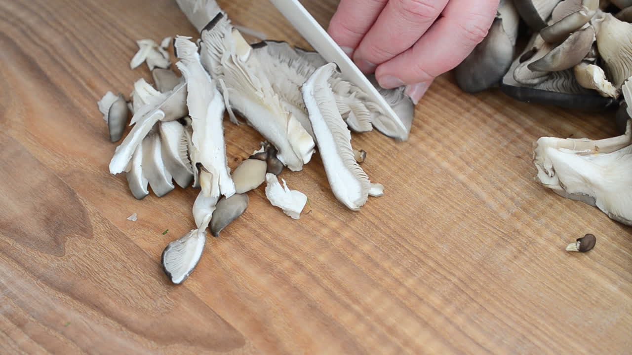 Tagliamo i funghi. Funghi pleurotus su un tagliere.