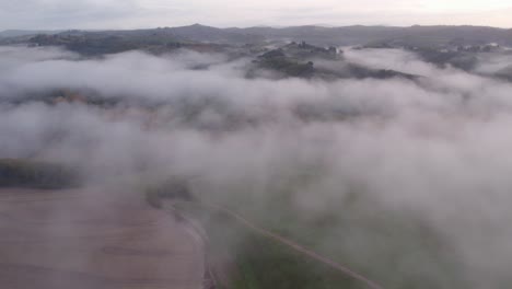 Rural-Italian-landscape-with-rolling-hills-covered-in-morning-mist,-aerial