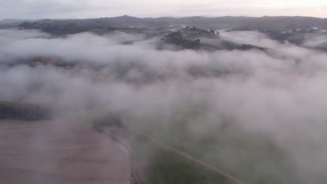 rural italian landscape with rolling hills covered in morning mist, aerial