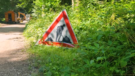 triangular warning sign in a bern forest alerts pedestrians to forestry work, its vivid red contrasting with lush summer greenery in switzerland