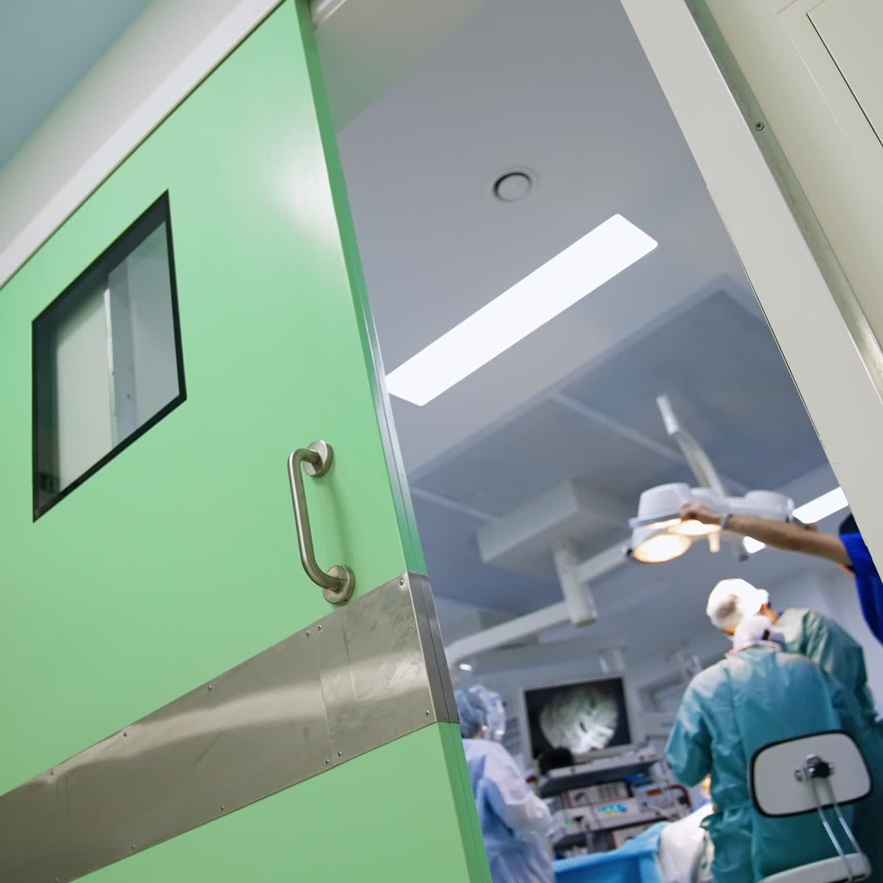 Group of doctors performing operation in modern hospitals. Gaze through the opened door to a surgery room. Low angle view