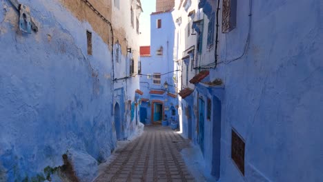 view looking up at half blue painted wall in chefchaouen with tilt down to reveal empty street