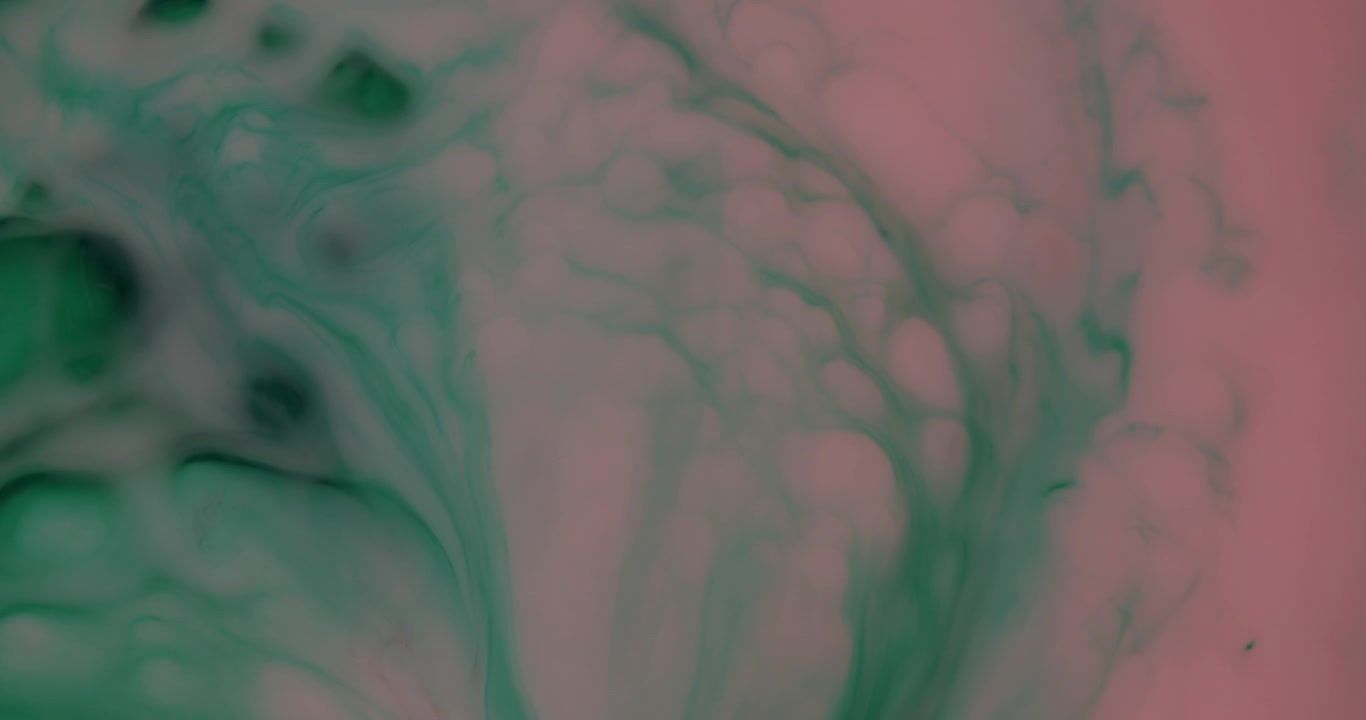 Macro top shot of pink colored milk mixed with green ink