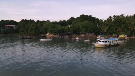 Drone-aerial-slow-move-backwards-with-Thai-boats-over-tropical-blue-water