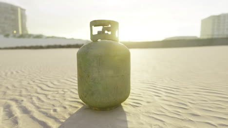 gas cylinder resting on sandy terrain during golden hour at the beach