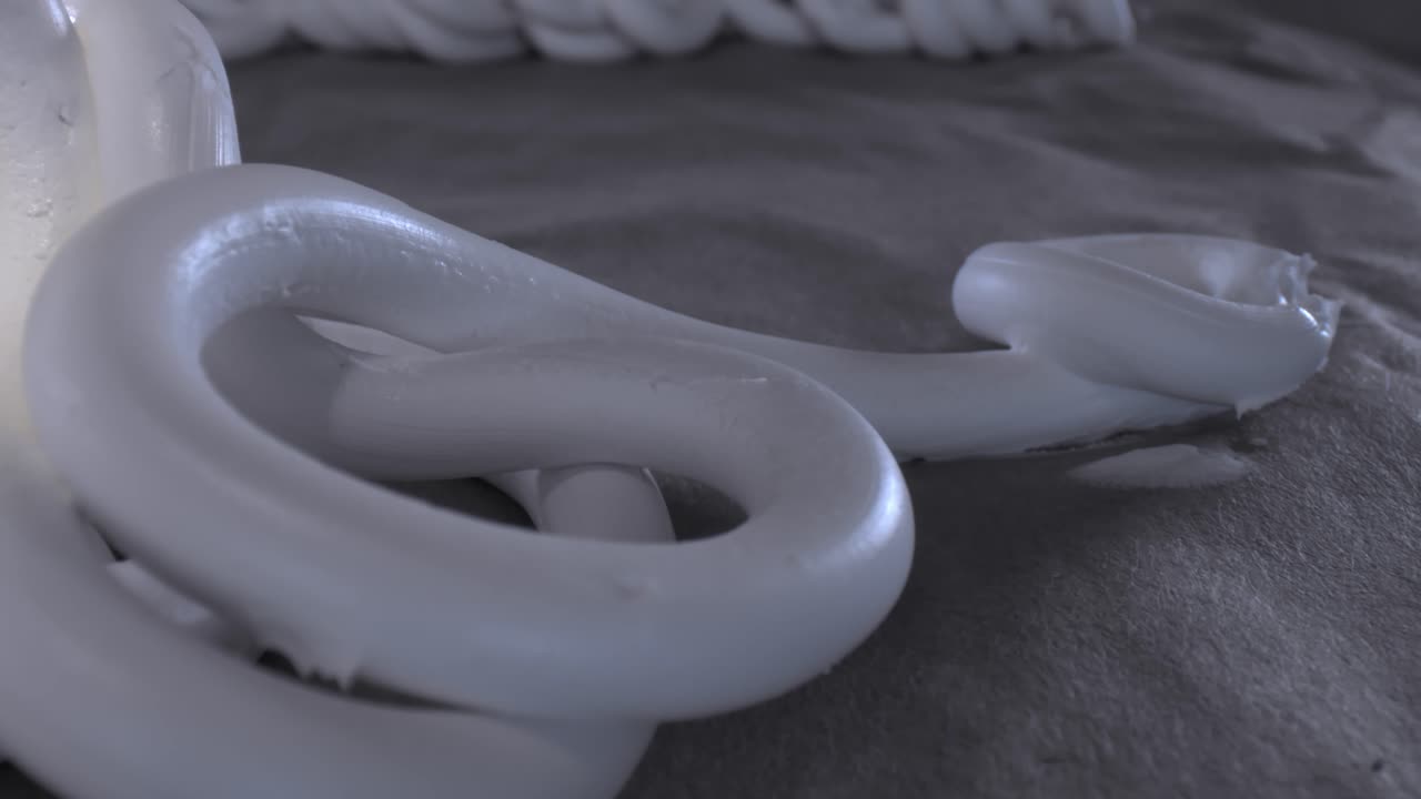 длинная нить материала в виде восьмерки в тени и темноте, переходящая влево на свет и показывающая множество других нитей белого материала, расположенных поперек в различном случайном порядке