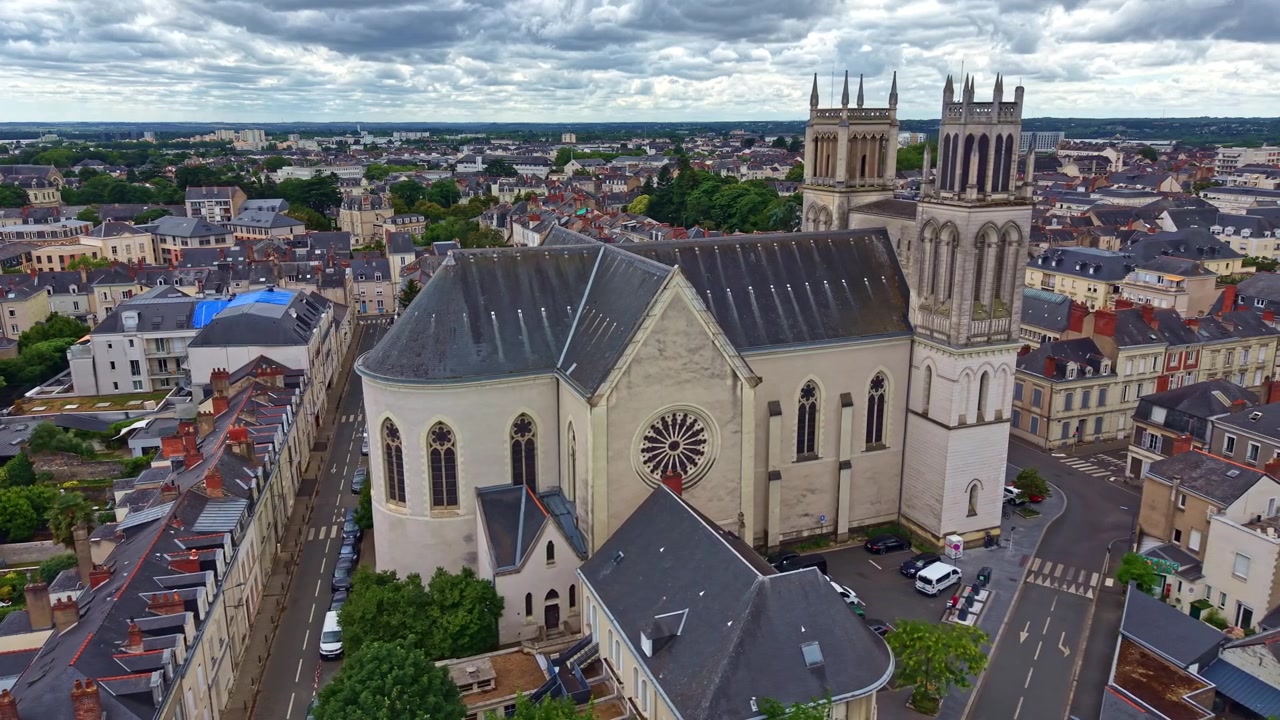 A Igreja de São José domina o horizonte de Angers, Maine-et-Loire, Pays de la Loire, França, cercada por ruas históricas, blocos residenciais e edifícios cívicos, em uma tomada de drone com deslizamento lateral para a direita.