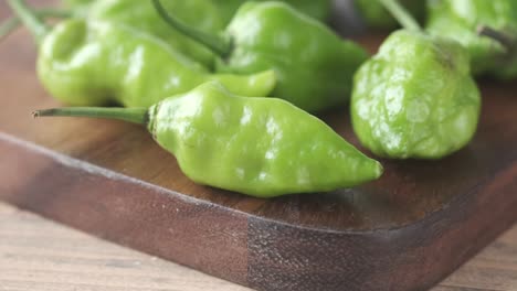 close-up of fresh green chili peppers on a wooden cutting board