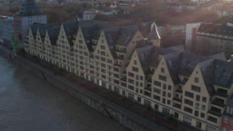 Slide-and-pan-shot-of-large-apartment-building-in-classical-style.-Houses-on-river-waterfront.-Cologne,-Germany